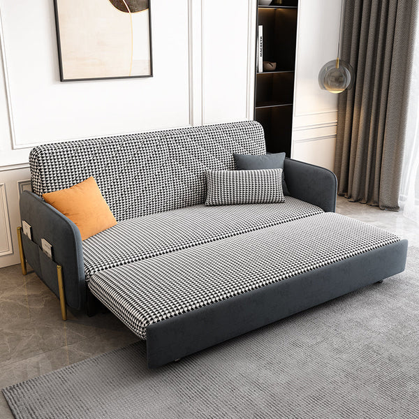 Gray and black checkered sofa bed in a room with a rug and wall art.