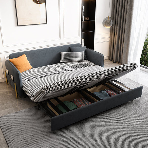 Gray velvet sofa bed with pull-out mechanism in a room with curtains and a rug.