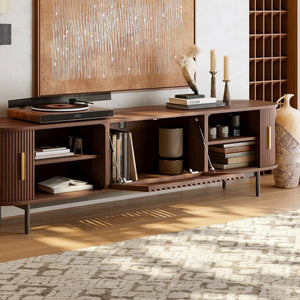 Walnut tv stand with sliding side doors and flip-down center door opening in a room with a rug and wall art.