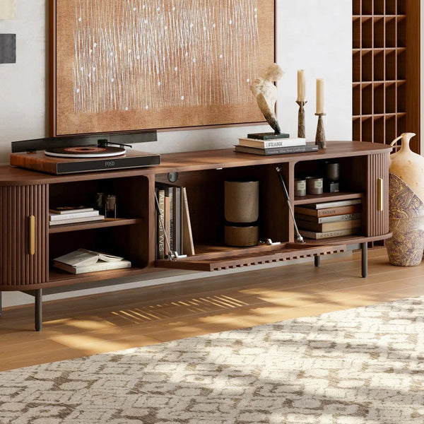 Walnut tv stand with sliding side doors and flip-down center door opening in a room with a rug and wall art.