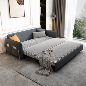 Gray velvet sleeper sofa with a blanket and pillows in a modern living room.